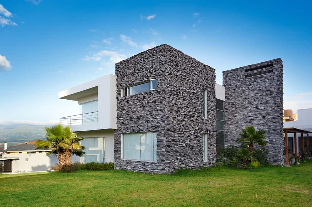 这是一座现代化的房子，一面是粉刷过的混凝土，另一面是耐用的石头外墙。