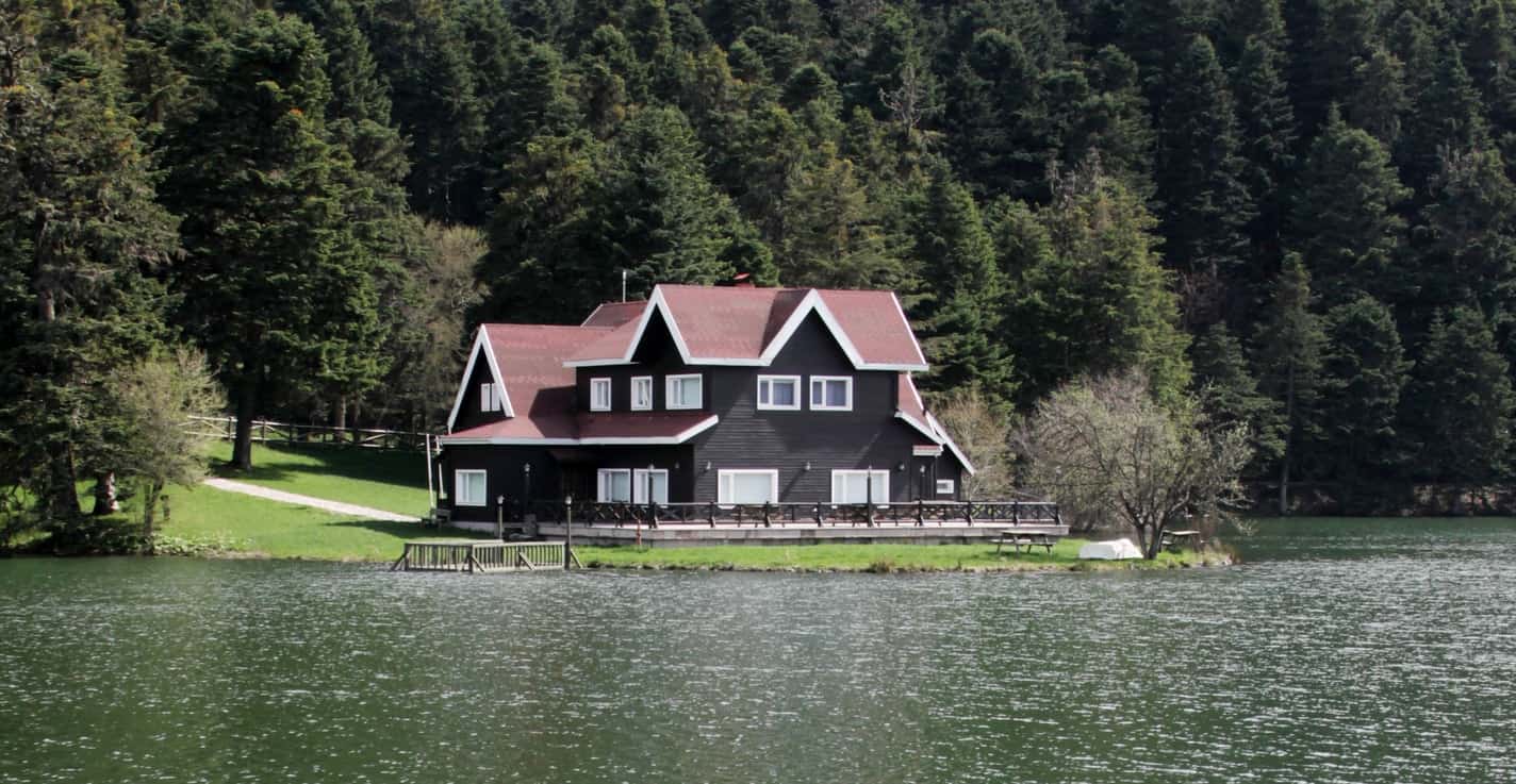 脆白概述这个湖房的屋顶峰和窗户。白色饰边也脱颖而出，靠红色屋顶和深色木板，可以轻松地融入绿色的风景中。