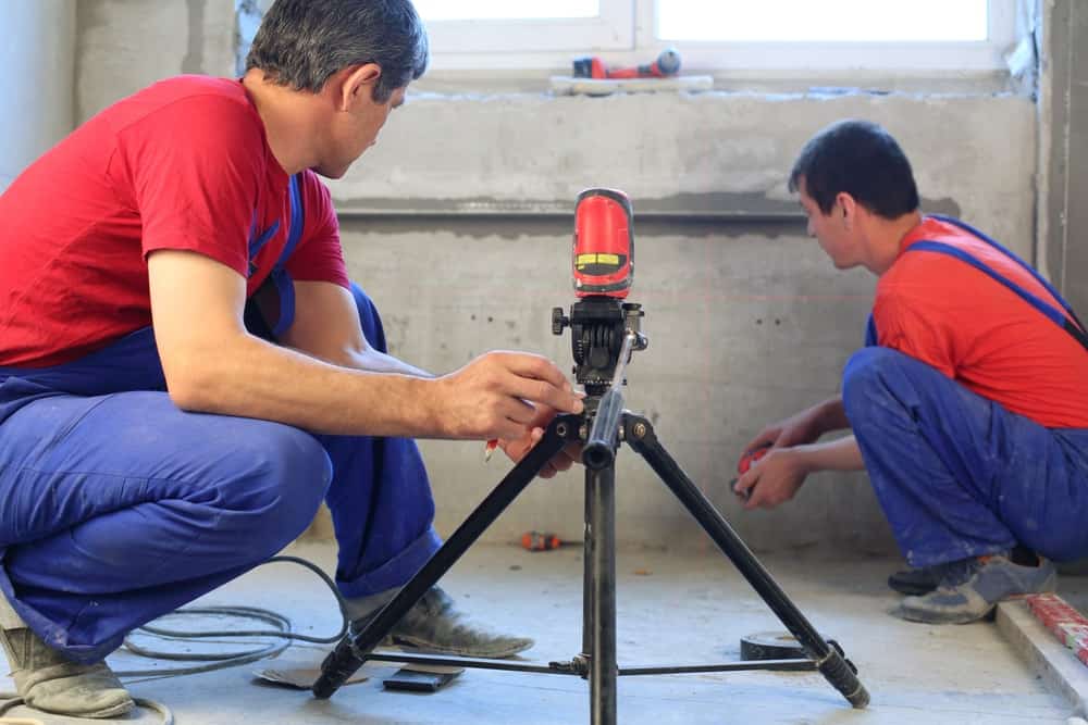 两名建筑工人正在使用激光水平来确定水泥应用的适用性。