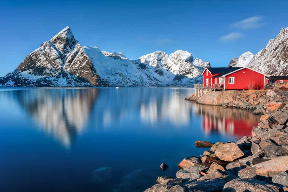 靠近挪威峡湾的岩石地产上的红色住宅。这张令人惊叹的照片展示了峡湾和不断上升的冰雪覆盖的落基山脉。有一天我也想去那里。