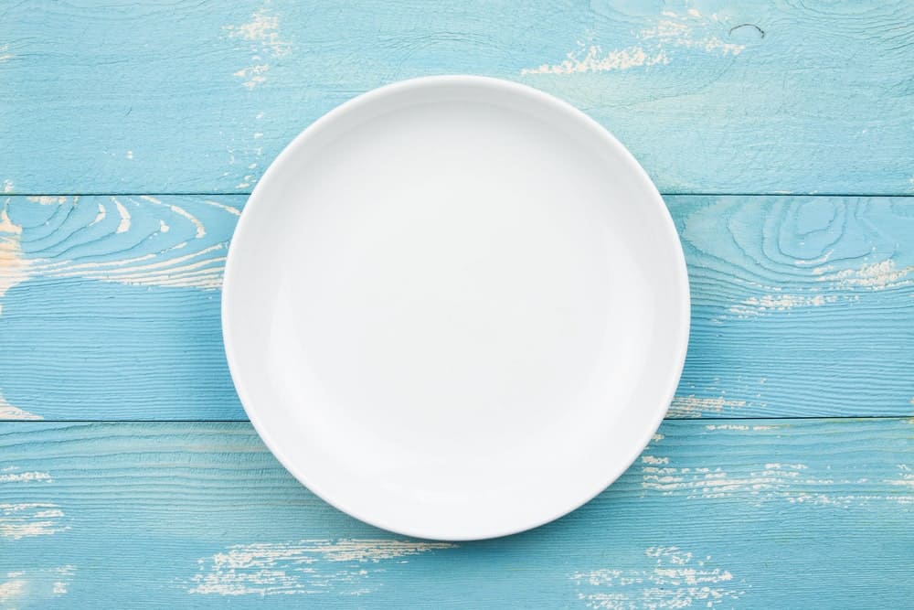 蓝漆木制背景上的白色圆盘子。