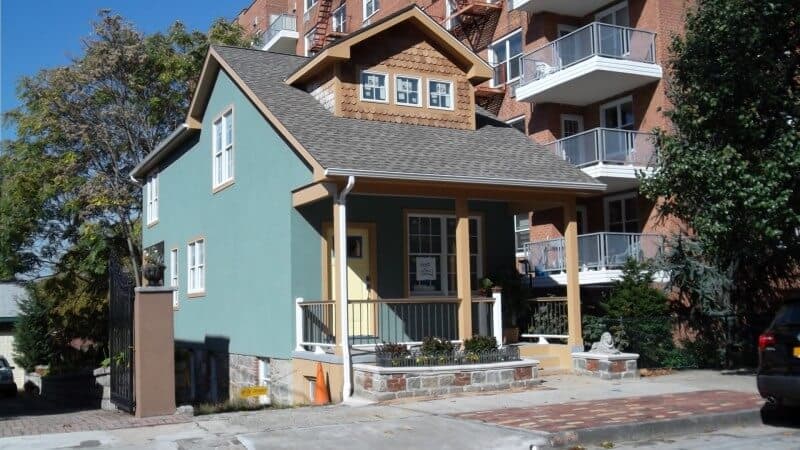 一座新装修的小房子，外观是绿色的。它也有一个小的门廊区域。