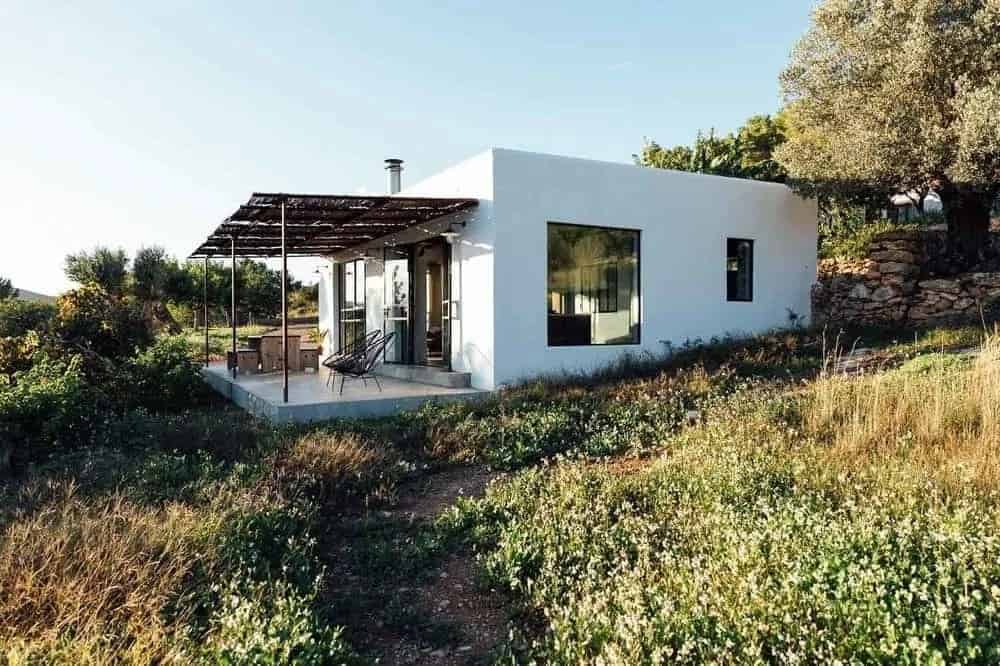 一个华丽而简单的小房子，白色外墙使其在其乡村风景周围的中间脱颖而出。设有户外用餐区和木质覆盖下的休息区，以更好地沉浸在景观中。