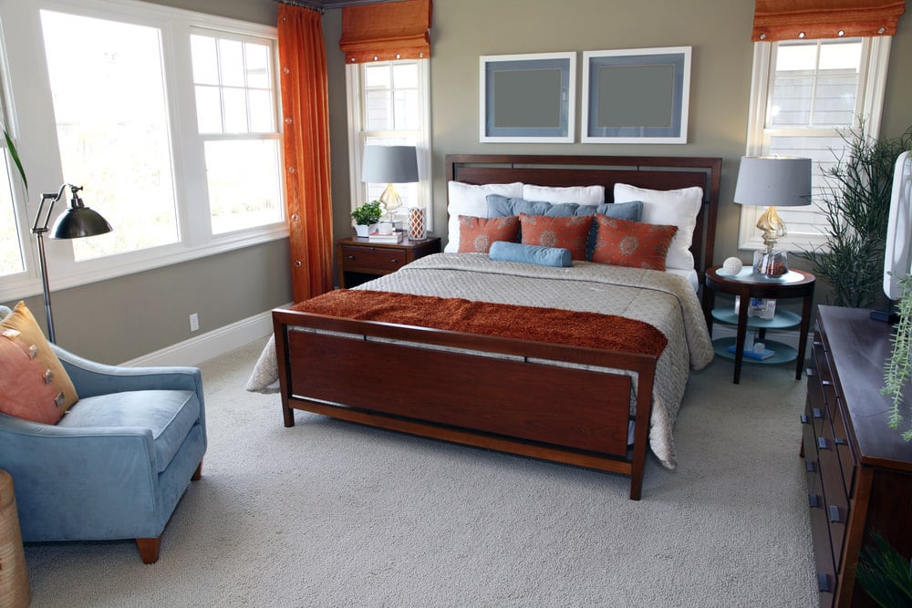 主要卧室以灰色地毯地板和灰色的墙壁为特色。它提供一个优雅的床设置，在床头柜顶上被灰色的台式灯照明。