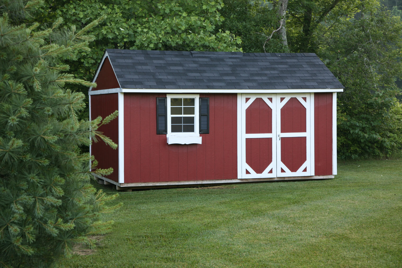 这个漂亮的红色小屋看起来像一个古老的乡村谷仓，有可爱的百叶窗和深色的石板屋顶。