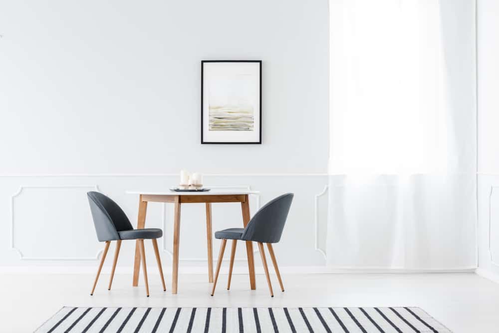 这是一个简单明亮的餐厅，白色的墙壁和地板使简单的饭桌脱颖而出。