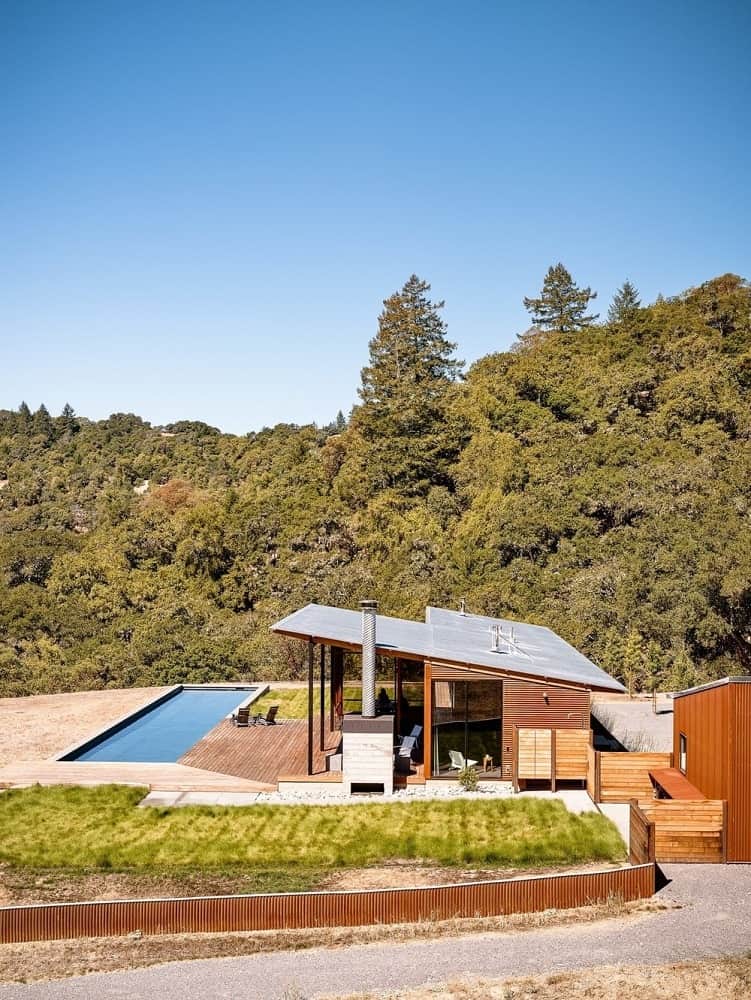 这个简单而迷人的住宅有一个倾斜的屋顶，与外部的木制面板和玻璃墙互补。这些玻璃窗和室外区域的设计是为了更好地欣赏周围的景观，以及后院美丽的游泳池和毛茸茸的草坪。