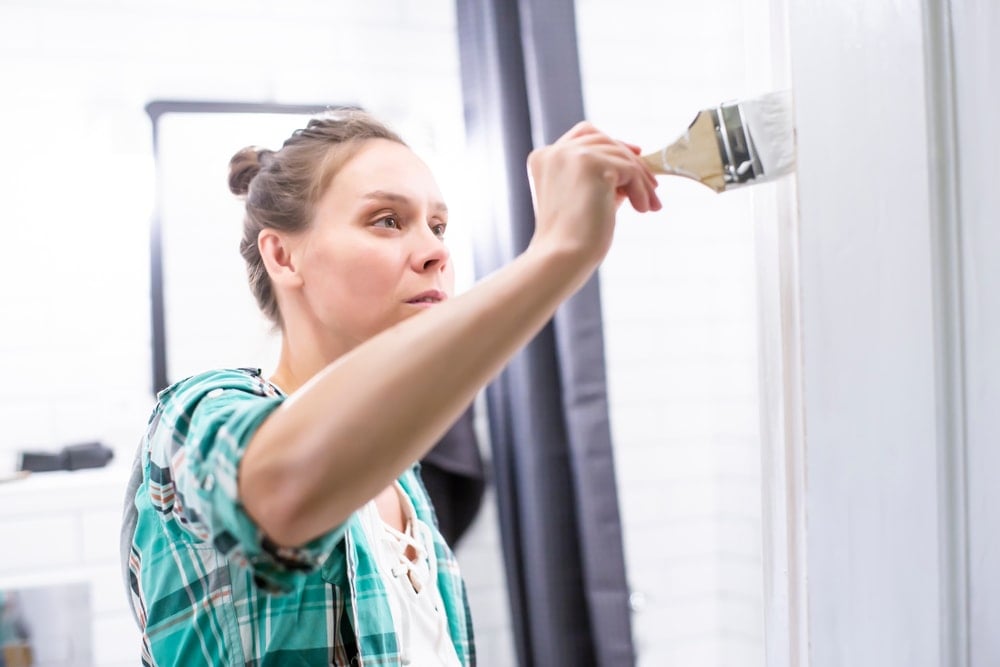 一个女人在粉刷她浴室的墙壁。