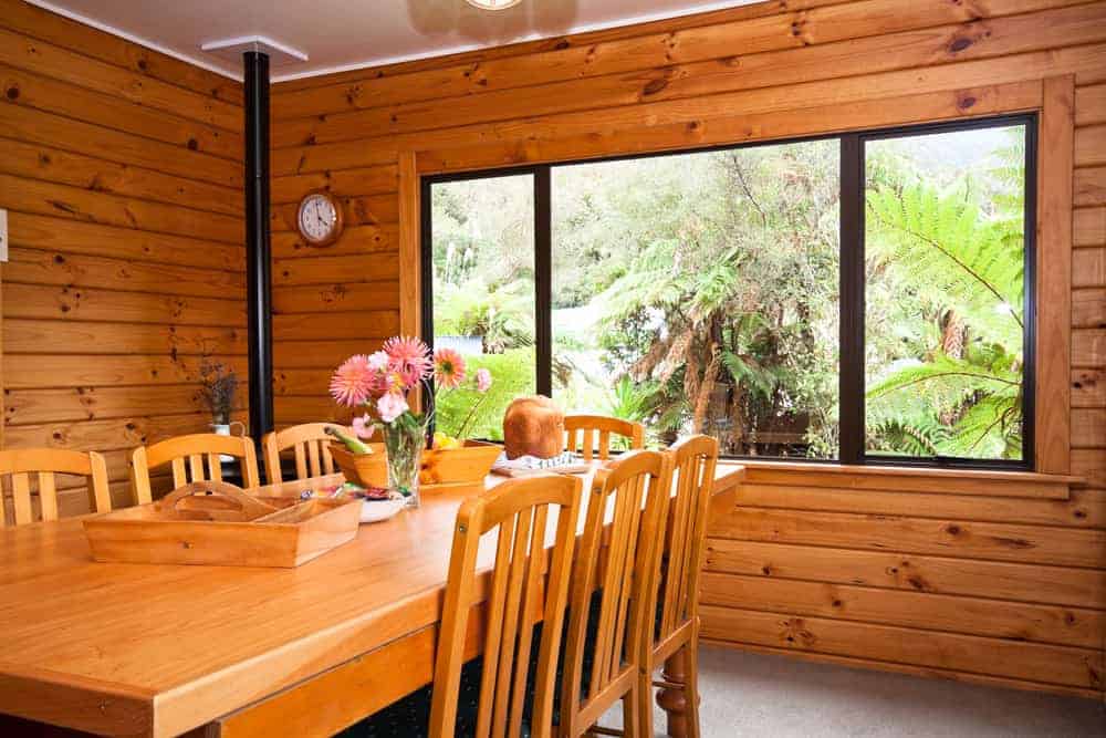 这是一张靠近山地山屋风格的用餐室，带木制船上的墙壁，大窗户和木制用餐套与墙壁的色调相匹配。