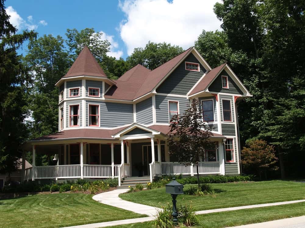 雄伟的房子，灰色的外观和美丽的庭院花园，有一条走道和维护良好的草坪。