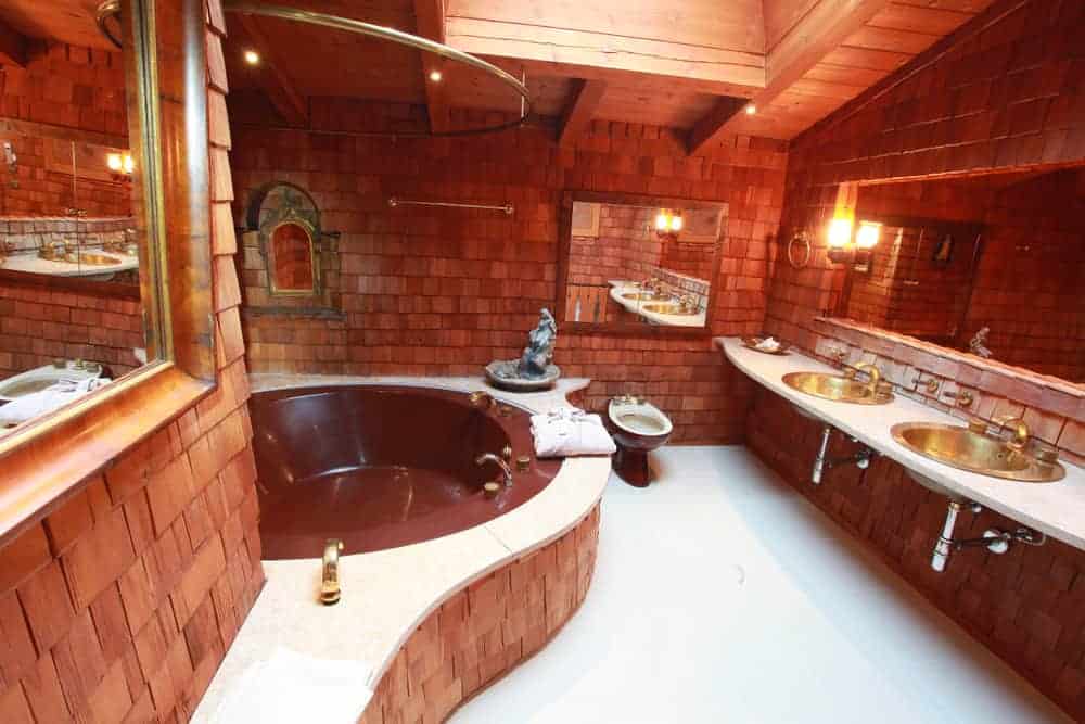 这是一间山间小屋风格的浴室，墙上有木瓦和镶板，形成了纹理图案，与浴缸和浮动的两水槽梳妆台互补，